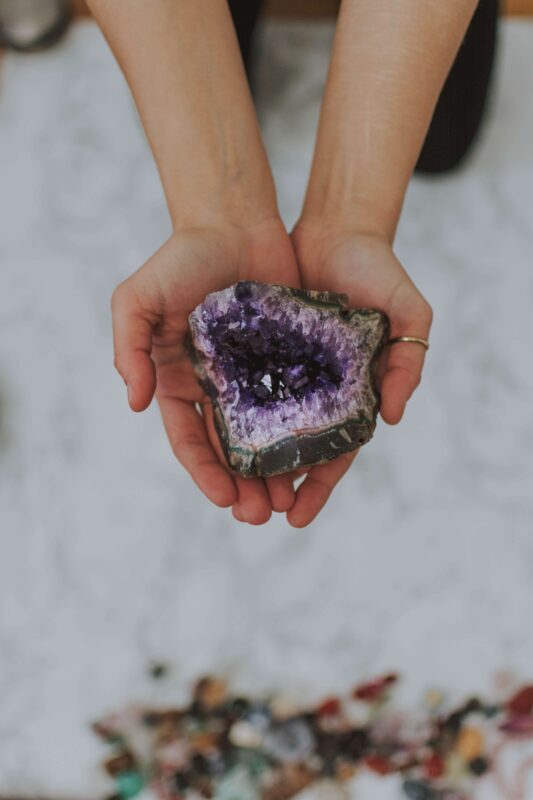 closeup shot girl holding multicolored rock her hands white surface (1)